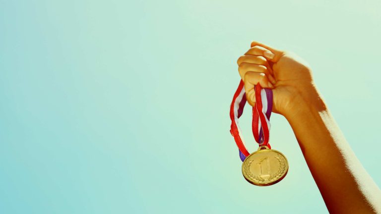 Decision Science | Arts & Culture Fundraising | Hand holding an Olympic gold metal - slide