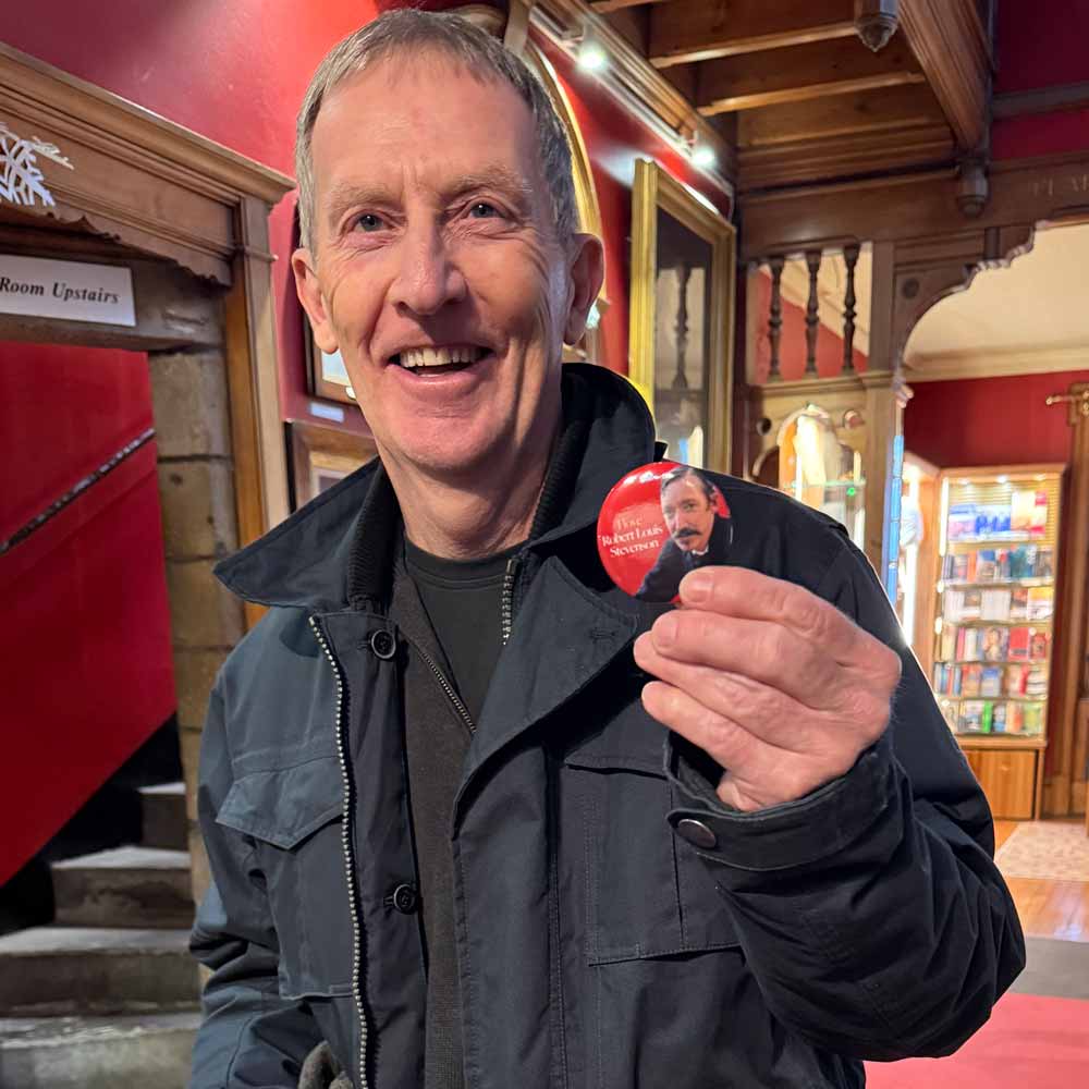 A man holding one of the pin badges we designed at the Writers' Museum